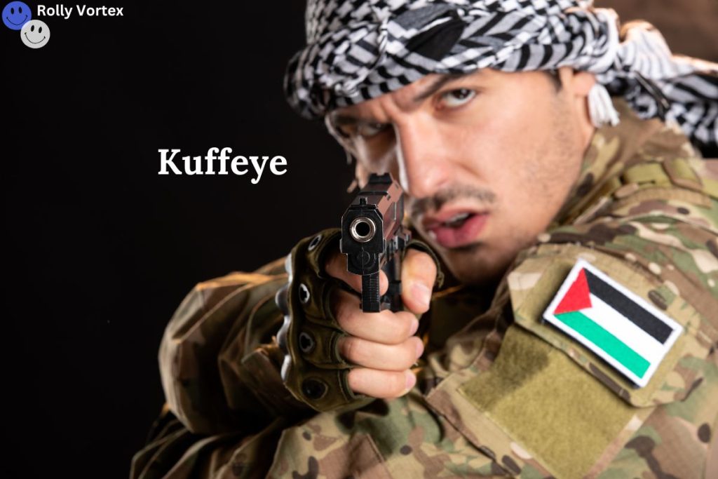 A man in military camouflage, wearing a black and white checkered keffiyeh, points a handgun directly at the camera. The Palestinian flag patch is visible on his uniform. The word "Kuffeye" is displayed in white text on the left side of the image. The image has a serious and intense tone.